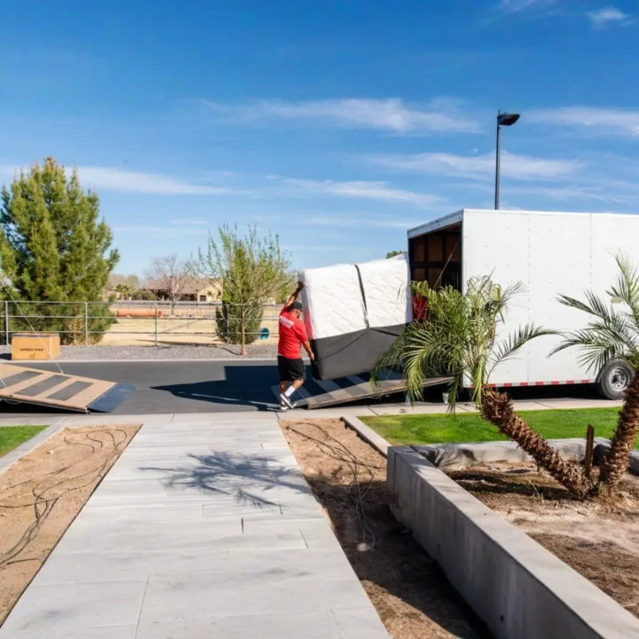 Midas Moving crew loading a large wrapped furniture item into a moving truck outside a home in Gilbert, AZ