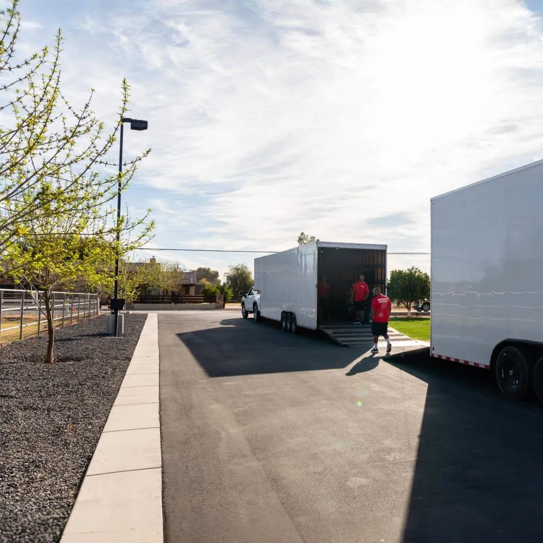 Midas Moving crew beside two enclosed moving trailers on a residential street in Gilbert, AZ