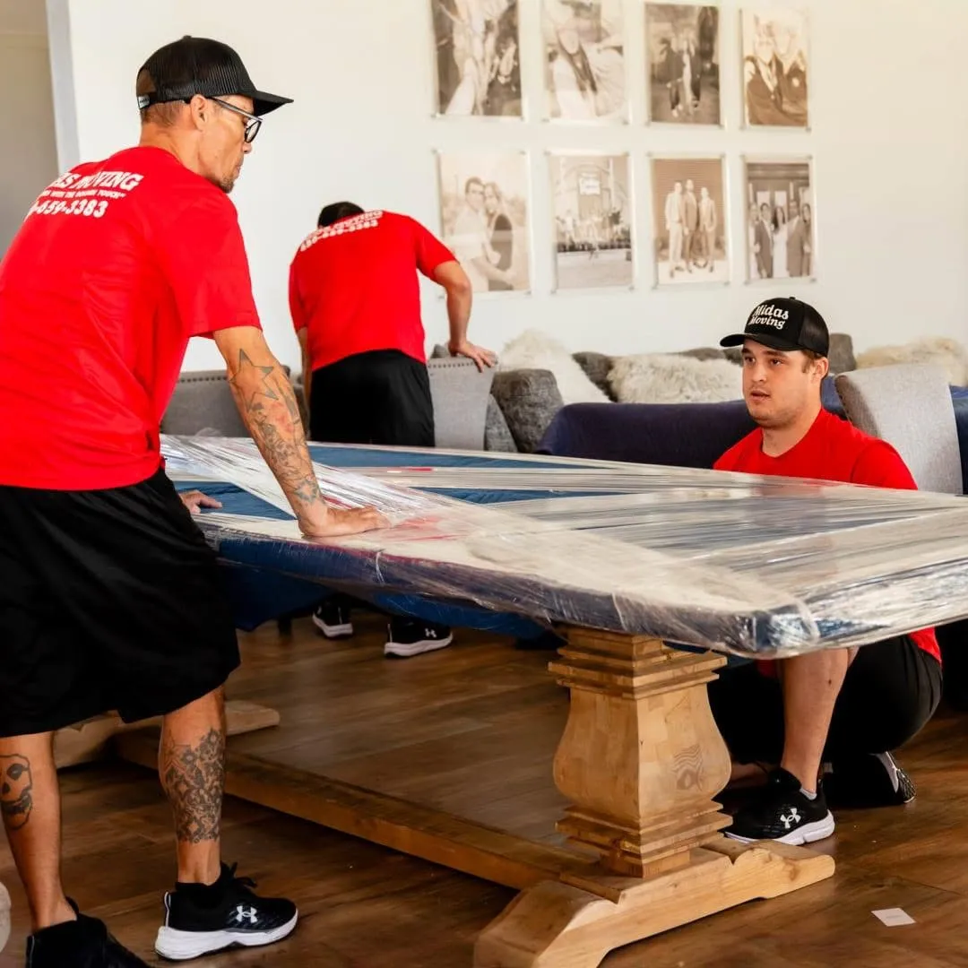 Midas Moving crew preparing a table protected with moving blankets and stretch wrap for transport in Gilbert, AZ