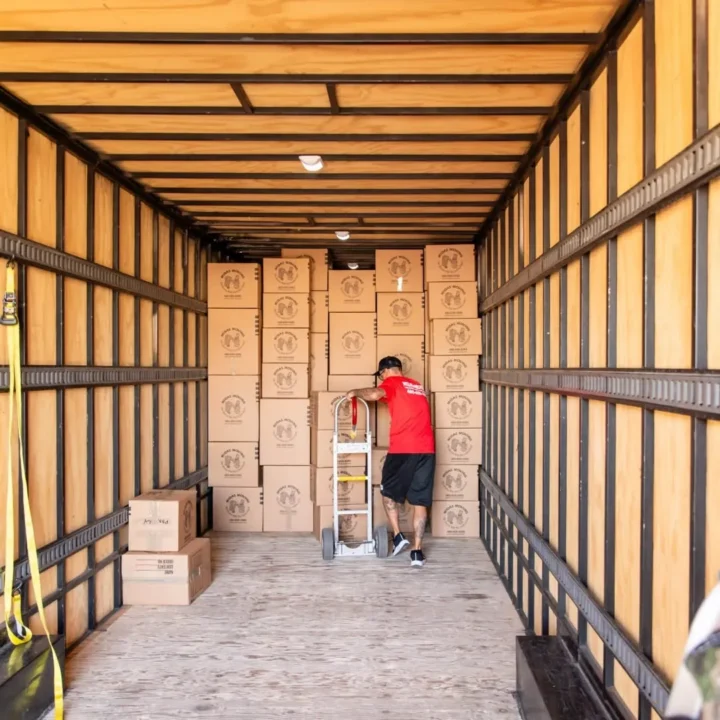 Midas Moving crew member with a hand truck beside neatly stacked boxes inside a moving trailer in Gilbert, AZ