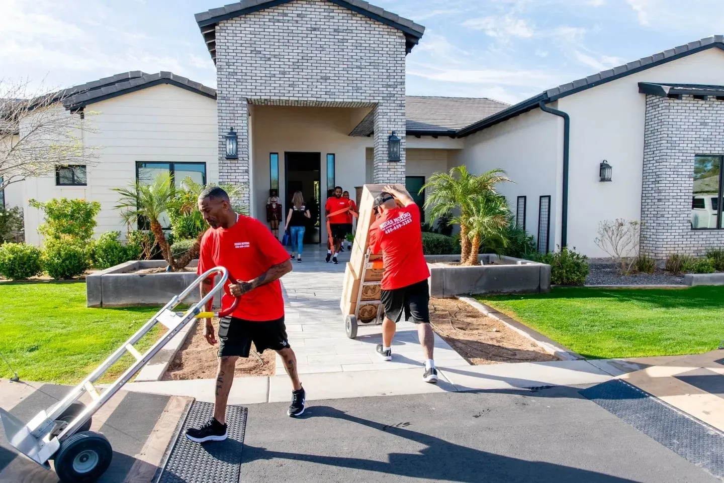 Midas Moving movers wheeling furniture and boxes out of a home on hand trucks